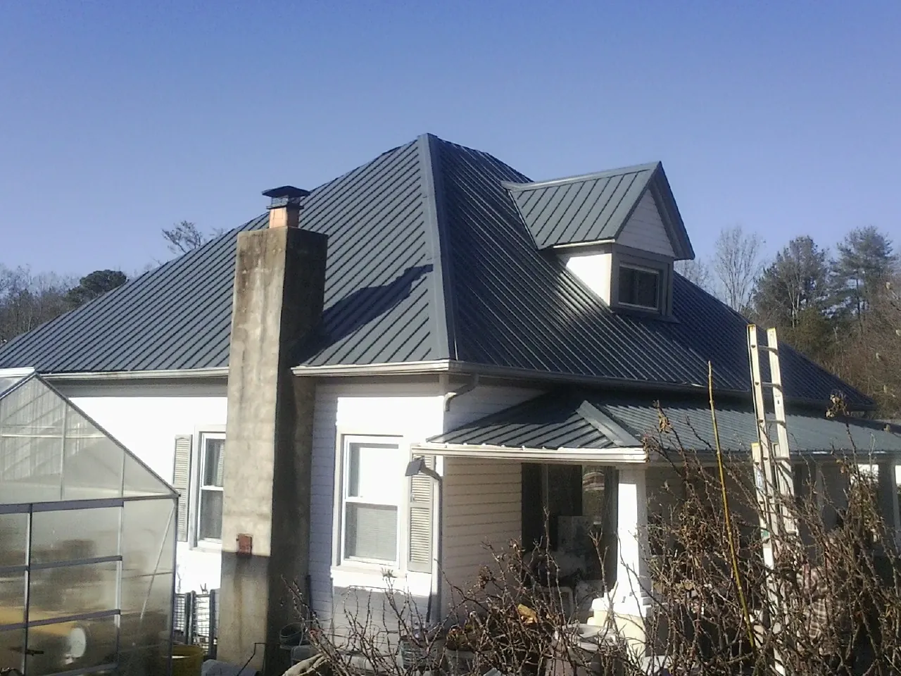Dark blue standing seam metal roof on a white farmhouse with dormer — Slate & Tile Roof Repair by Roofing Brothers in Binghamton