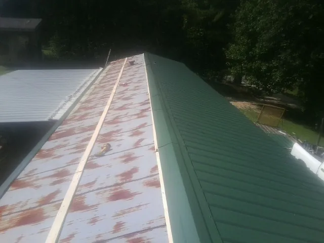 Old rusted panels beside newly installed green metal roofing — Wind Damage Roof Repair by Roofing Brothers in Binghamton