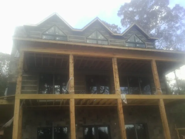 Dormers and porch framing on a large log home under construction — Roof Coating work by our crew in Binghamton