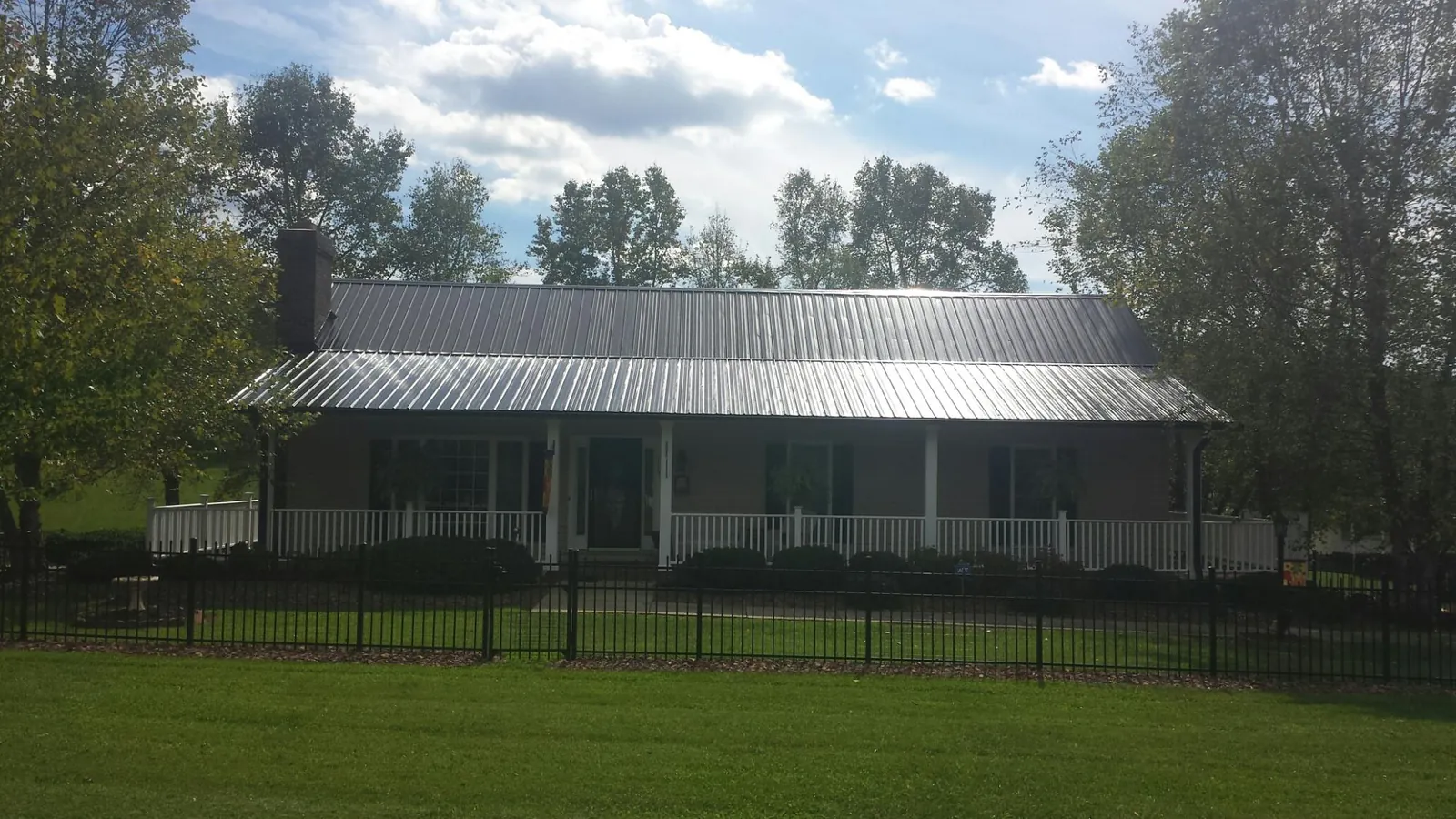 Gray metal roof on a brick ranch with a full width front porch — Gutter Guard Installation work by our crew in Binghamton
